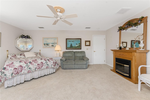 carpeted bedroom with ceiling fan, visible vents, and a glass covered fireplace