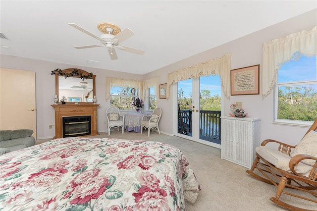 bedroom featuring light carpet, visible vents, a glass covered fireplace, ceiling fan, and access to outside