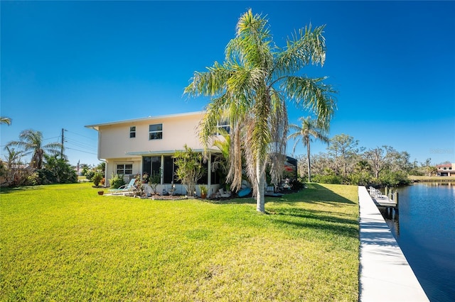 rear view of house with a water view, a lawn, and stucco siding