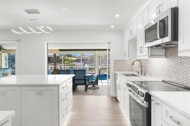 2160 Palm Tree Dr, Punta Gorda, FL 33950 - kitchen with appliances with stainless steel finishes, white cabinets, light wood-type flooring, light countertops, and recessed lighting