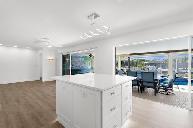 2160 Palm Tree Dr, Punta Gorda, FL 33950 - kitchen with a center island, light wood-style flooring, white cabinets, light countertops, and recessed lighting