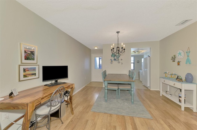 dining space featuring a textured ceiling, a chandelier, and light hardwood / wood-style floors