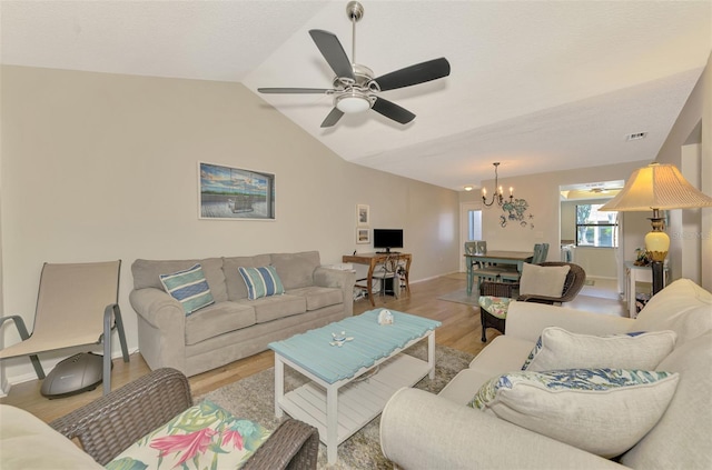 living room featuring hardwood / wood-style flooring, ceiling fan with notable chandelier, and lofted ceiling