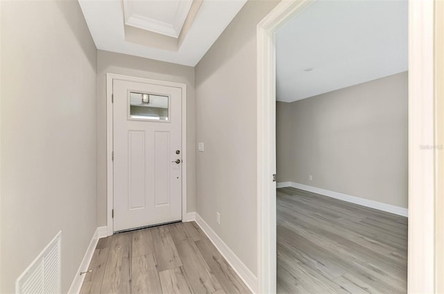 entryway featuring baseboards, a tray ceiling, visible vents, and light wood-style floors