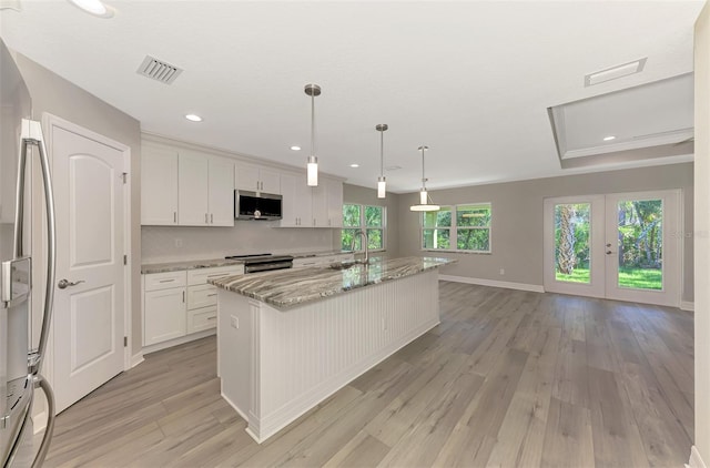 kitchen with visible vents, stainless steel appliances, a kitchen island with sink, and white cabinetry