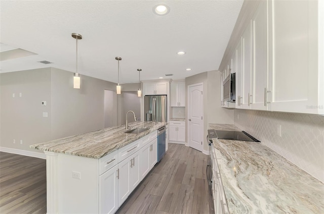 kitchen featuring stainless steel appliances, white cabinets, light wood-type flooring, an island with sink, and pendant lighting