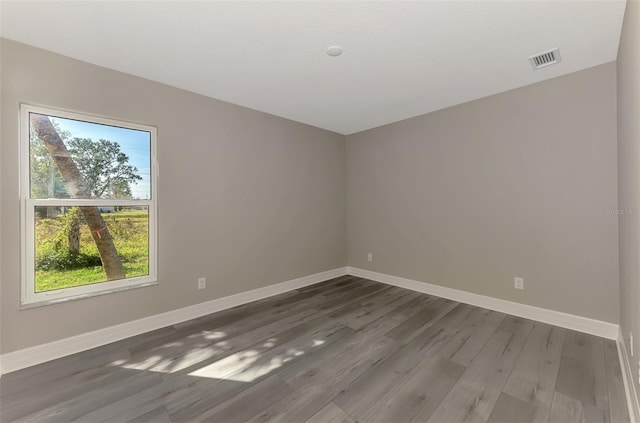 unfurnished room featuring baseboards, visible vents, and dark wood-style flooring