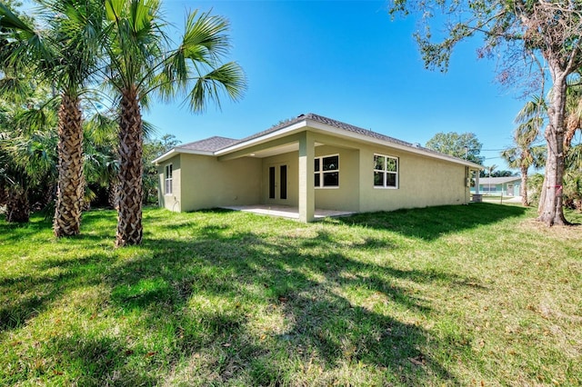 back of property with a patio, a lawn, and stucco siding