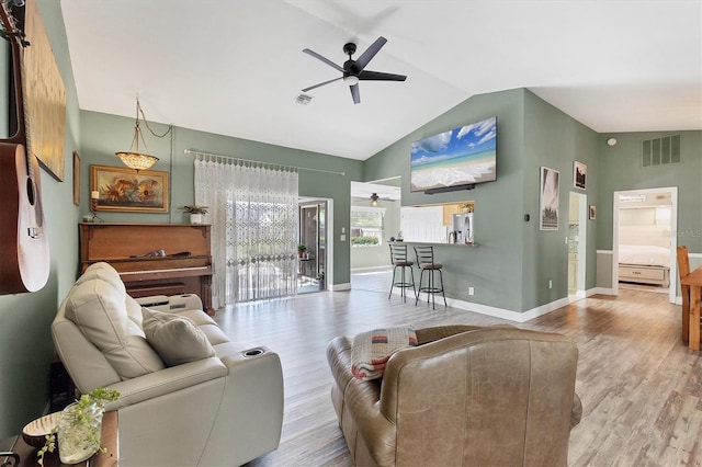 living area featuring light wood-style floors, vaulted ceiling, visible vents, and ceiling fan