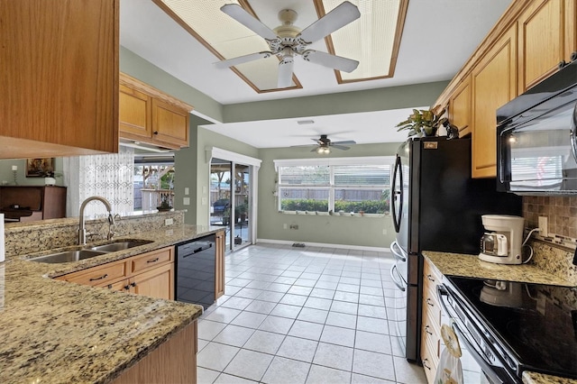 kitchen with light tile patterned floors, tasteful backsplash, a sink, light stone countertops, and black appliances