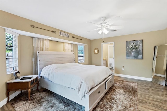 bedroom featuring visible vents, ensuite bathroom, a ceiling fan, wood finished floors, and baseboards