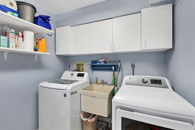 washroom with a sink, washing machine and clothes dryer, and cabinet space