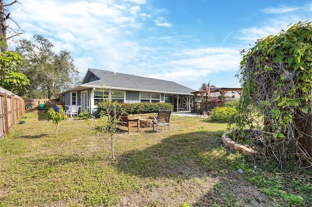 rear view of property featuring a yard and a fenced backyard