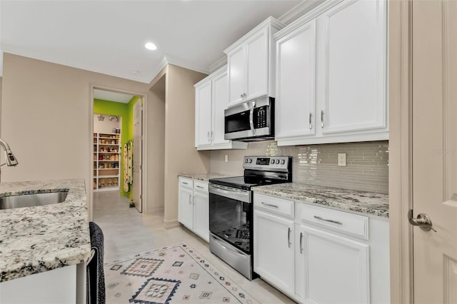 kitchen with light stone counters, sink, stainless steel appliances, and white cabinets