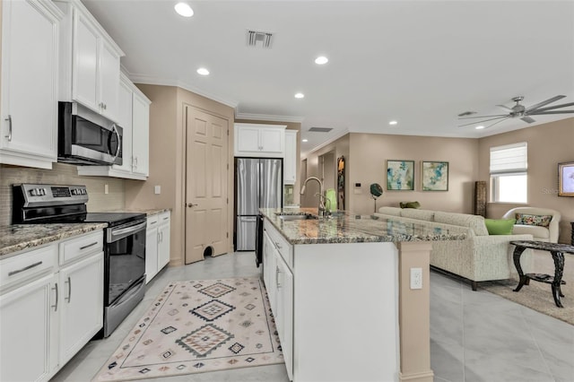 kitchen featuring sink, white cabinetry, appliances with stainless steel finishes, an island with sink, and light stone countertops