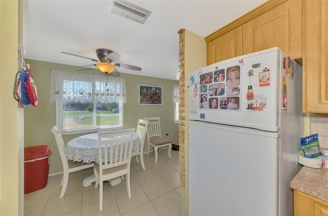 kitchen with light tile patterned flooring, white refrigerator, ceiling fan, and light brown cabinetry