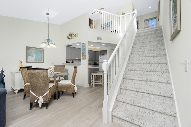 2255 N Beach Rd Unit 13, Englewood, FL 34223 - dining area featuring visible vents, light wood-style flooring, a high ceiling, stairs, and a chandelier