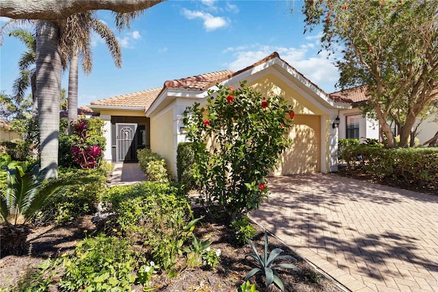 view of front facade featuring a garage, decorative driveway, stucco siding, and a tile roof