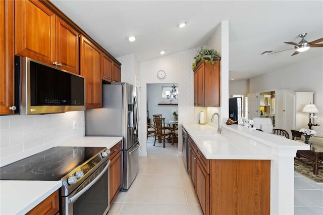 kitchen with light tile patterned floors, lofted ceiling, a peninsula, a sink, and appliances with stainless steel finishes