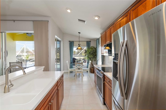 kitchen with visible vents, lofted ceiling, a sink, stainless steel appliances, and brown cabinets