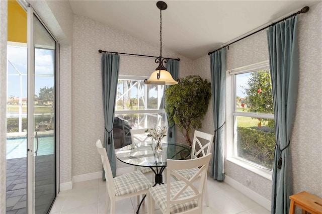 dining space featuring wallpapered walls, baseboards, light tile patterned flooring, and vaulted ceiling