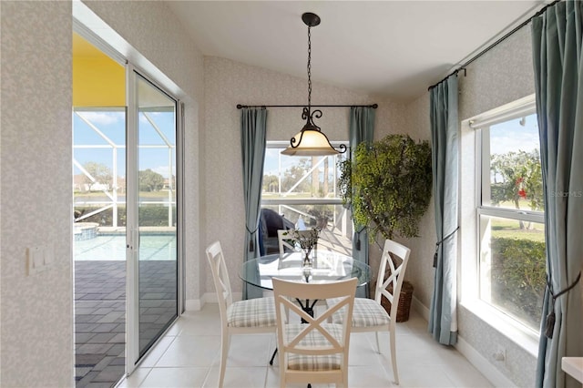 dining room featuring light tile patterned floors, lofted ceiling, a healthy amount of sunlight, and wallpapered walls