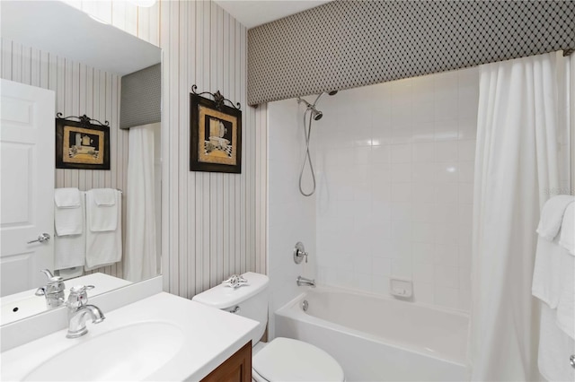 bathroom featuring toilet, wallpapered walls, vanity, and shower / tub combo