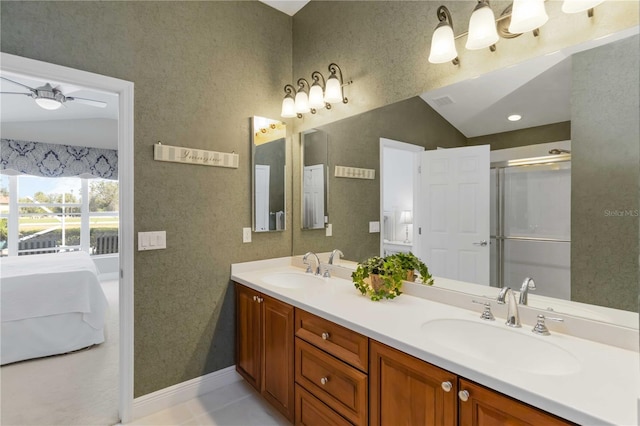 ensuite bathroom featuring a sink, ceiling fan, and vaulted ceiling