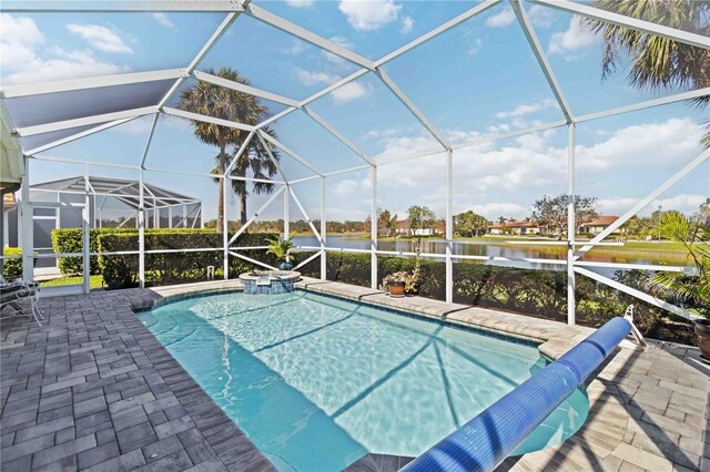 view of pool featuring glass enclosure, a patio, a water view, and a pool with connected hot tub