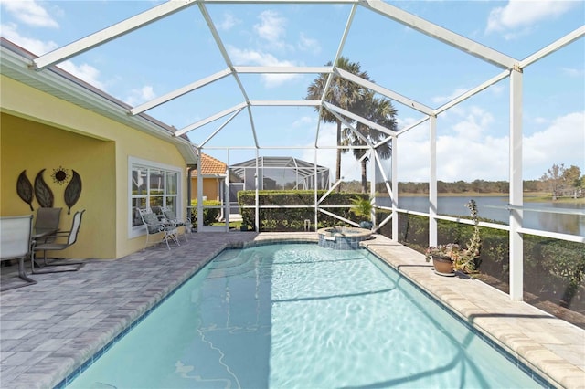 view of swimming pool featuring glass enclosure, a water view, a pool with connected hot tub, and a patio area