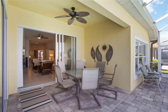 view of patio / terrace featuring outdoor dining space, a lanai, and a ceiling fan