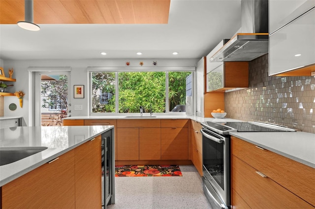 kitchen featuring wall chimney range hood, stainless steel range with electric stovetop, decorative backsplash, sink, and wine cooler