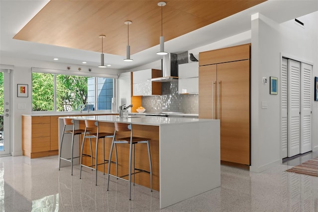 kitchen featuring tasteful backsplash, hanging light fixtures, white cabinetry, a kitchen island with sink, and paneled fridge