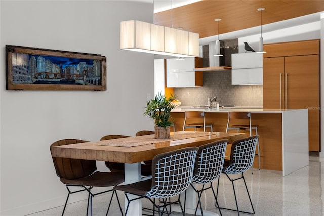 kitchen featuring hanging light fixtures, wall chimney exhaust hood, a breakfast bar area, and kitchen peninsula