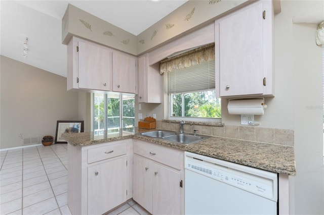 kitchen with visible vents, light tile patterned flooring, a sink, dishwasher, and a peninsula