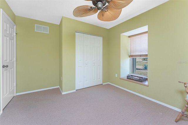 unfurnished bedroom with baseboards, visible vents, a closet, and light colored carpet