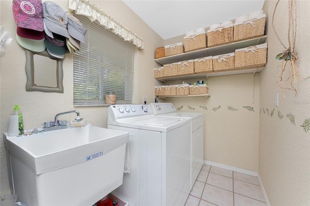 laundry room featuring light tile patterned flooring, a sink, laundry area, independent washer and dryer, and baseboards