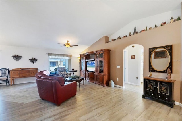 living room with arched walkways, ceiling fan, lofted ceiling, baseboards, and light wood-style floors