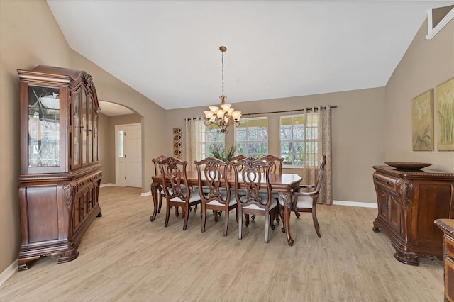 dining room with vaulted ceiling, arched walkways, light wood-style flooring, and baseboards