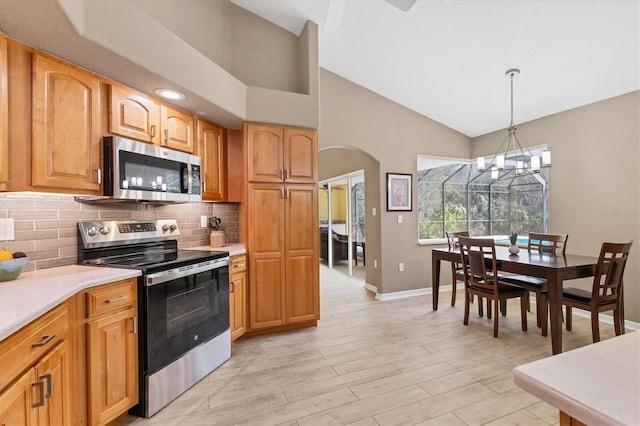 4050 Rock Creek Dr, Port Charlotte, FL 33948 - kitchen featuring arched walkways, light countertops, appliances with stainless steel finishes, hanging light fixtures, and backsplash