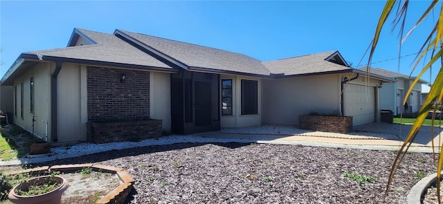 single story home featuring a garage, concrete driveway, brick siding, and roof with shingles