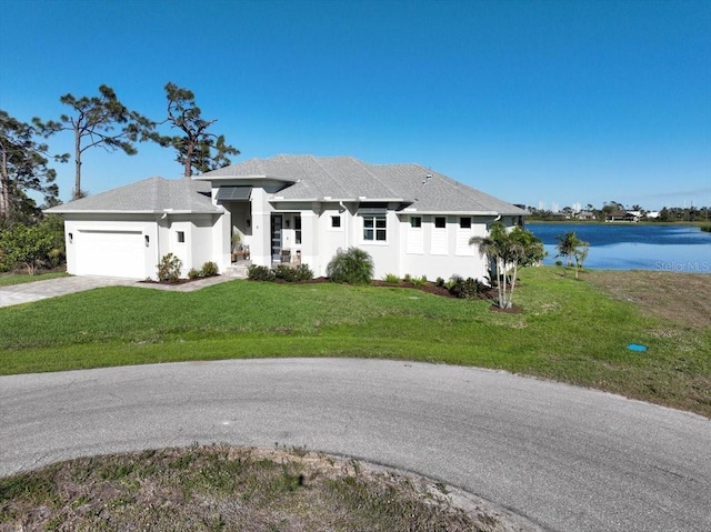 view of front of home featuring driveway, a garage, a water view, a front lawn, and stucco siding