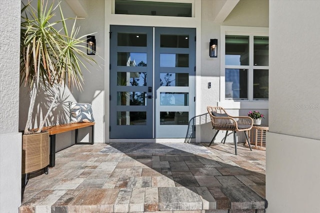 property entrance with french doors, a patio area, and stucco siding