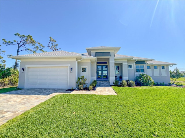 prairie-style house with a garage, a front yard, decorative driveway, and stucco siding