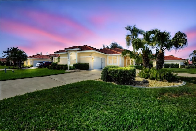 mediterranean / spanish home with concrete driveway, a yard, an attached garage, and stucco siding