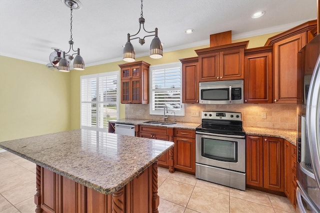 kitchen with a kitchen island, glass insert cabinets, appliances with stainless steel finishes, hanging light fixtures, and a sink