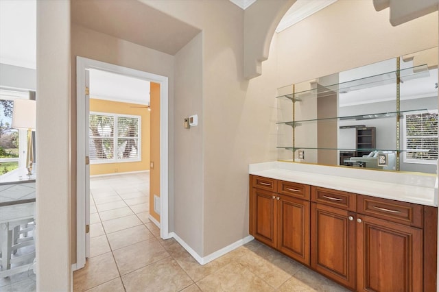 bar with arched walkways, crown molding, light tile patterned floors, visible vents, and baseboards