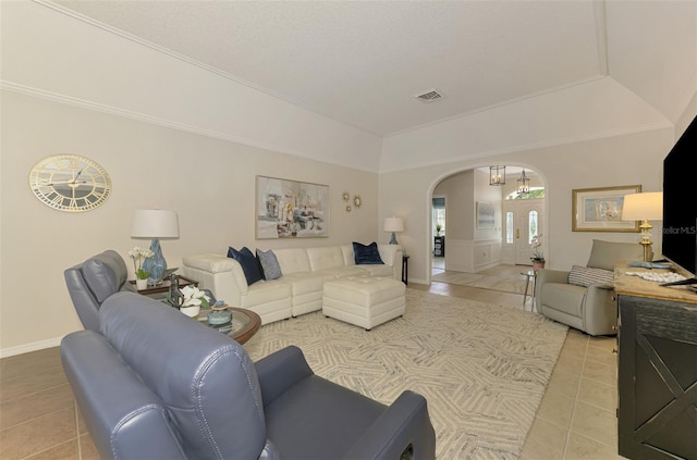 living room with arched walkways, light tile patterned floors, vaulted ceiling, and visible vents