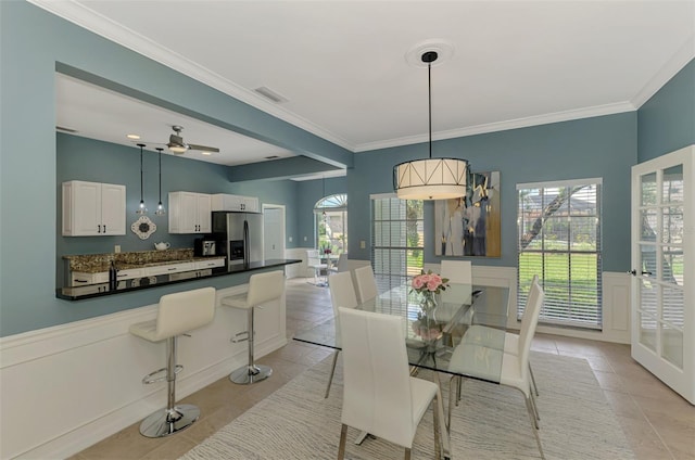 dining space with a wainscoted wall, ornamental molding, light tile patterned floors, and visible vents