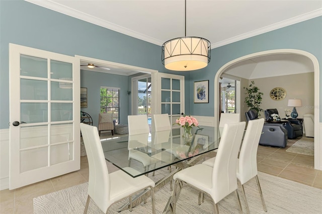 dining room with arched walkways, ornamental molding, light tile patterned flooring, and a ceiling fan